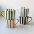 Set of three striped mugs on a marble surface with a white background