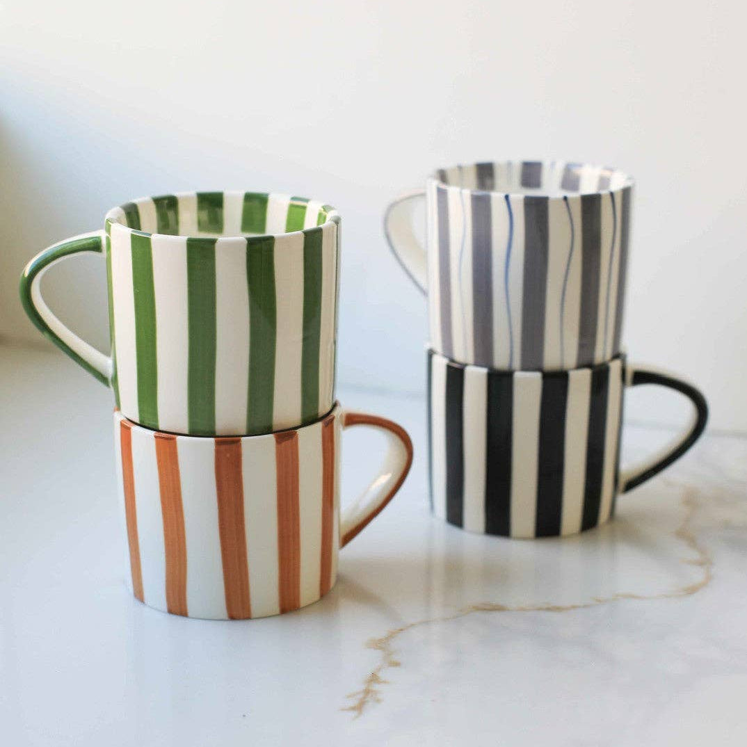Set of three striped mugs on a marble surface with a white background