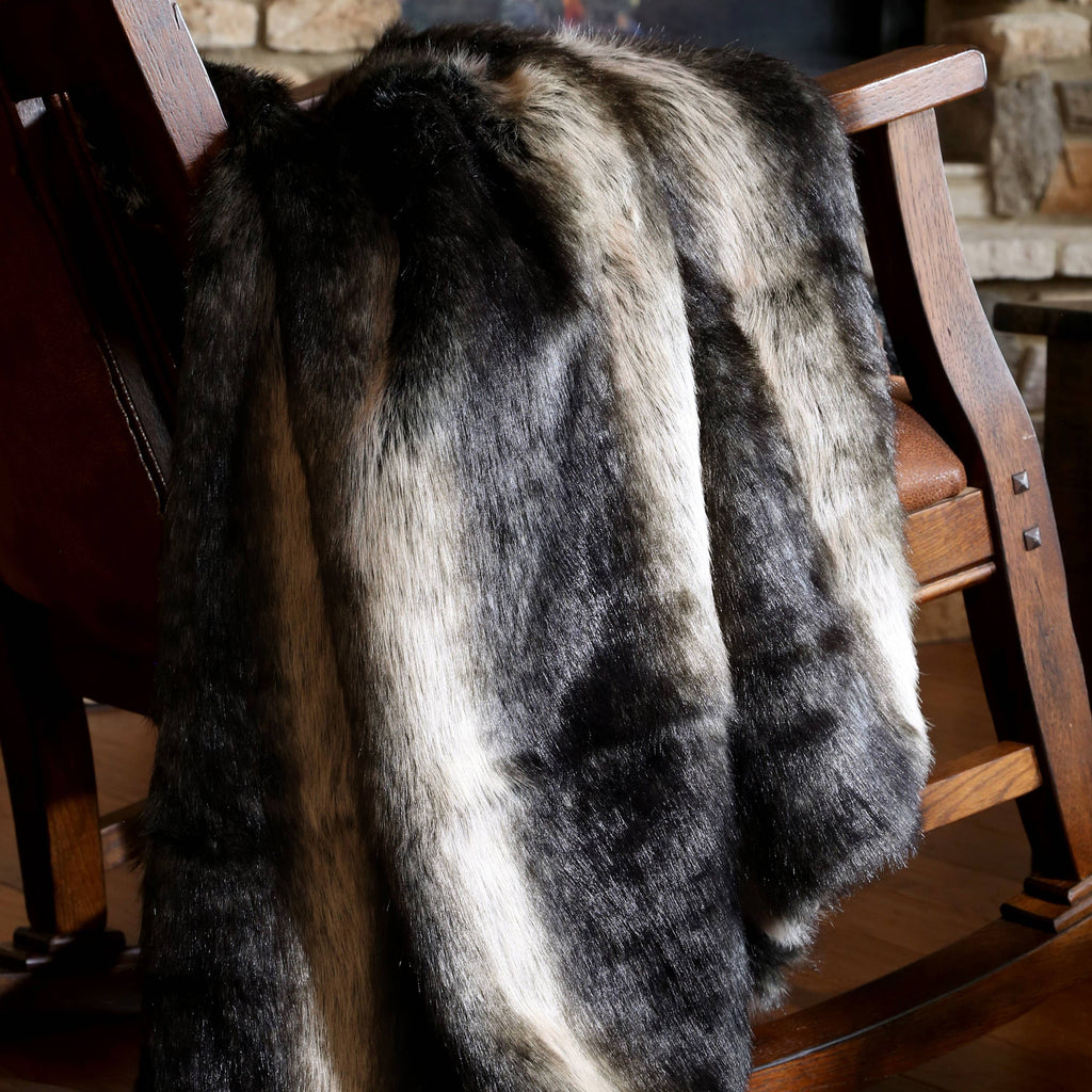 Fur throw draped over a wooden chair in front of a fireplace.